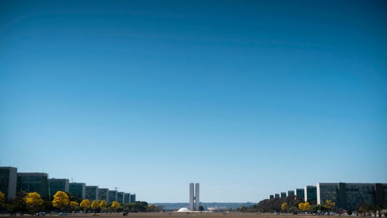 Esplanada dos Ministérios e Congresso Nacional em Brasília, com ipês-amarelos floridos sob céu azul