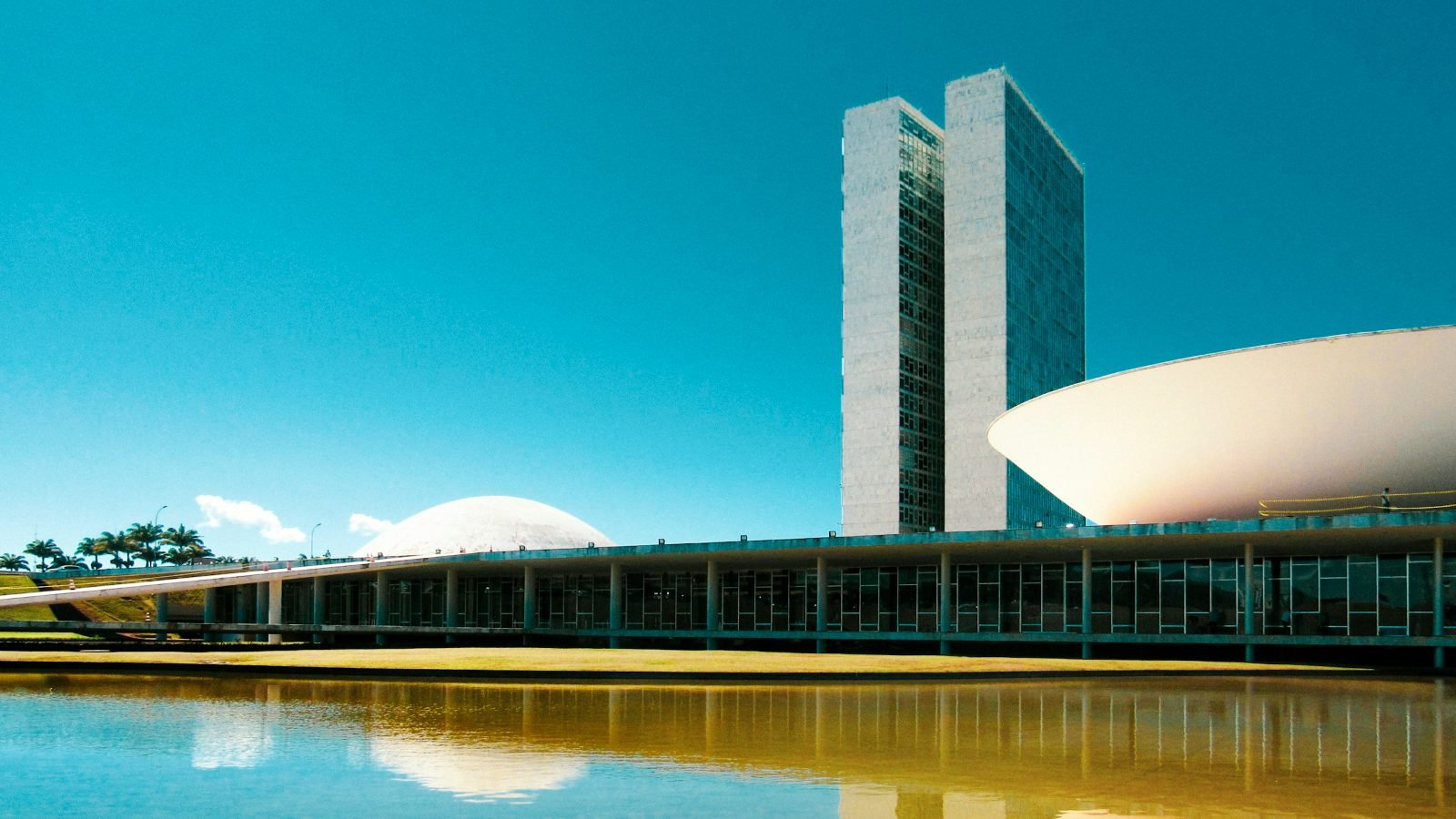 Congresso Nacional e o espelho d'água na Praça dos Três Poderes, em Brasília, sob céu azul