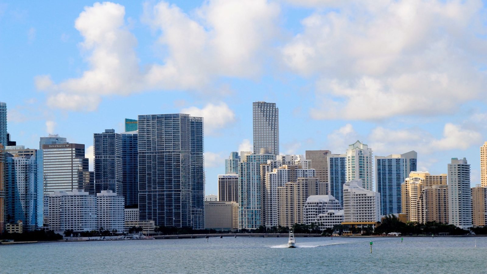 Arranha-céus de vidro à beira d'água no centro de Miami, vistos da baía em dia de céu azul