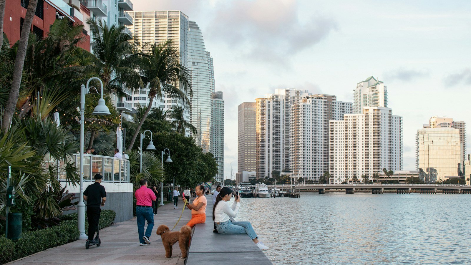 Calçadão à beira d água em Brickell, Miami, com prédios residenciais ao fundo no fim da tarde