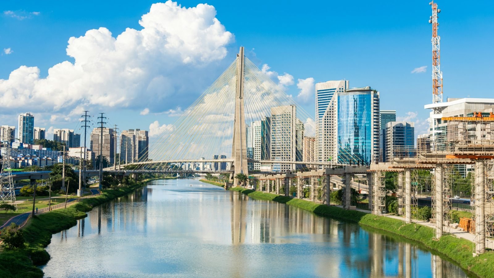 Ponte Estaiada sobre o Rio Pinheiros, em São Paulo, com prédios espelhados e céu azul com nuvens